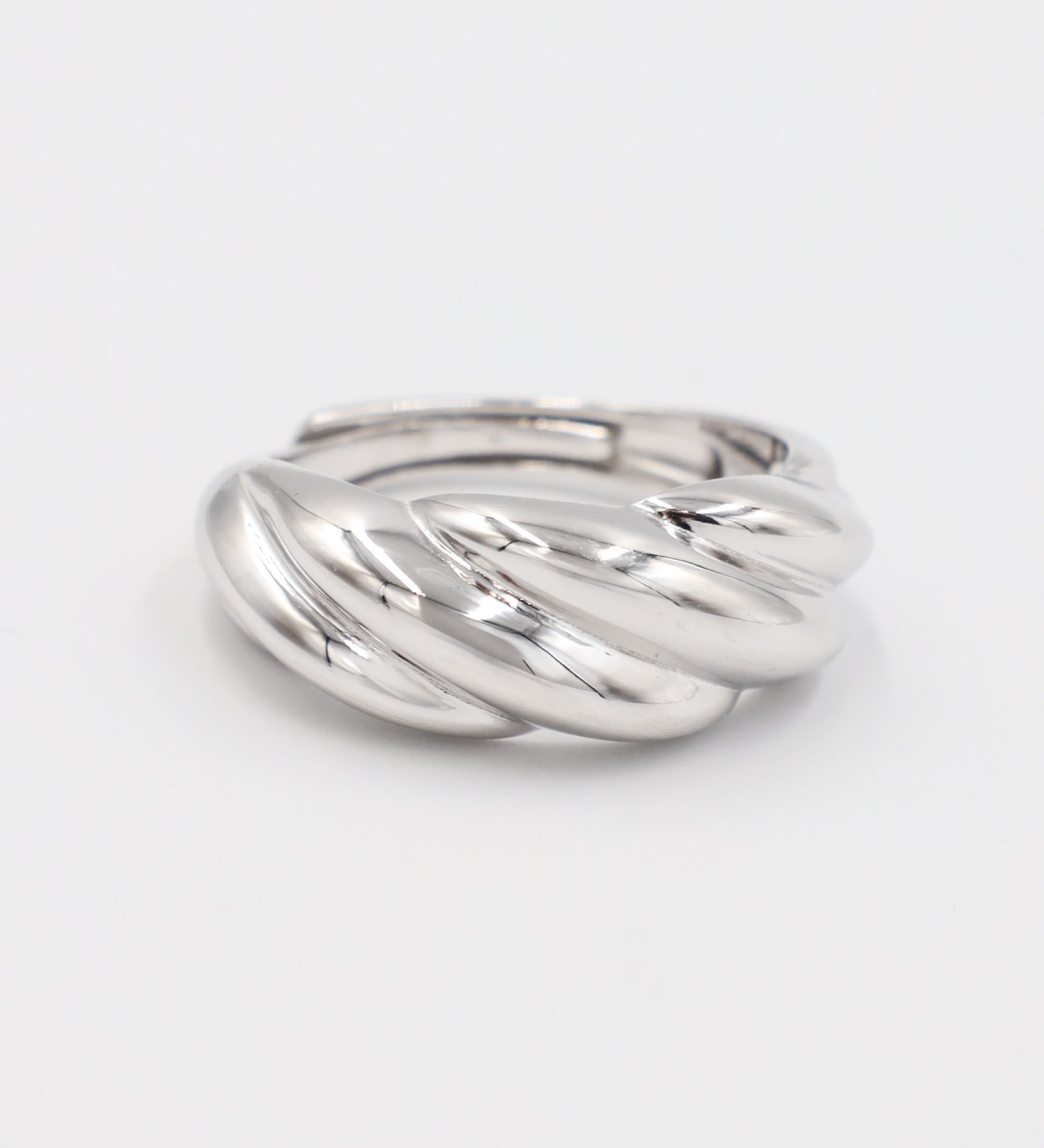 A silver-colored ring with a twisted design on a white background.