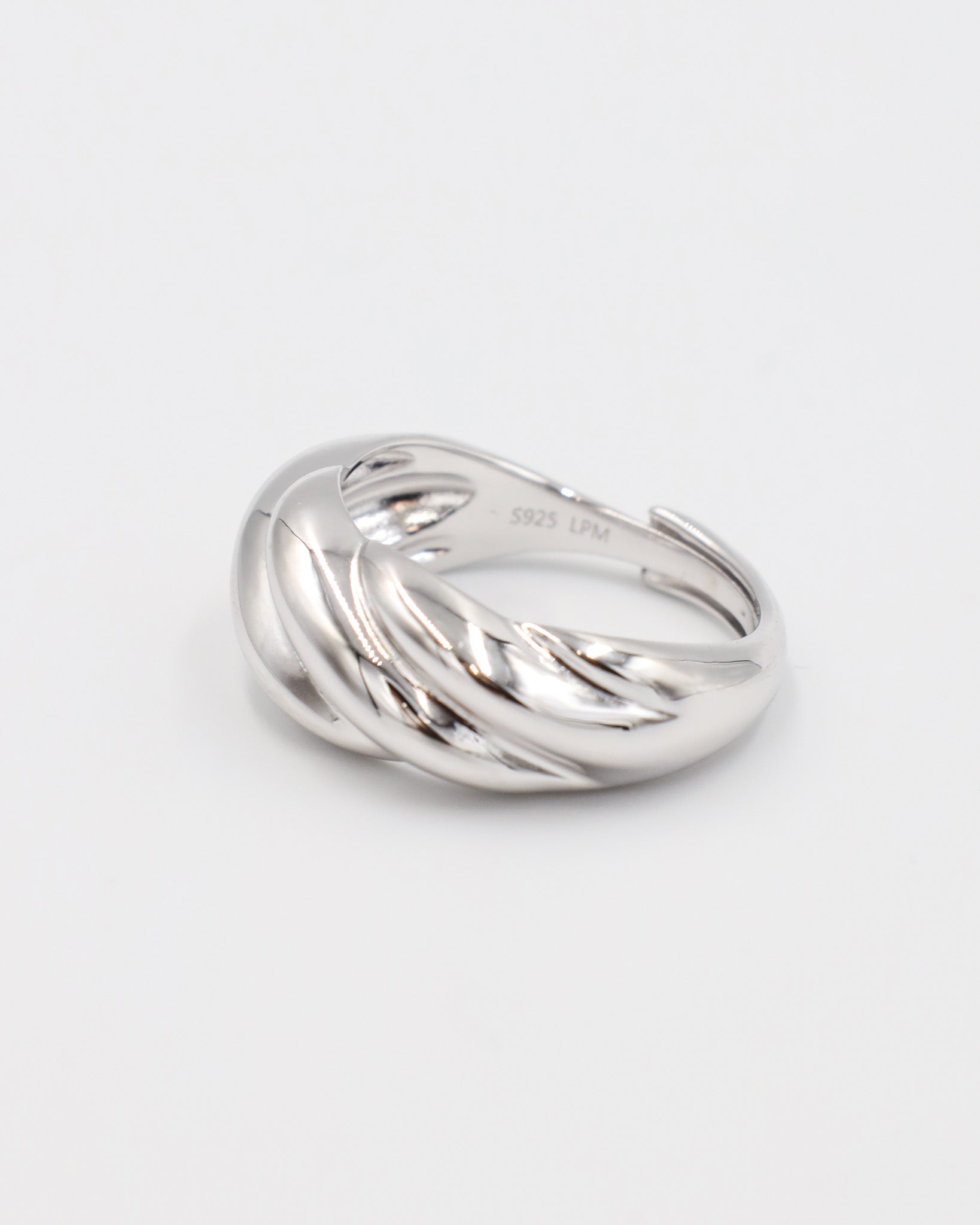 A silver-colored ring with a twisted design on a white background.