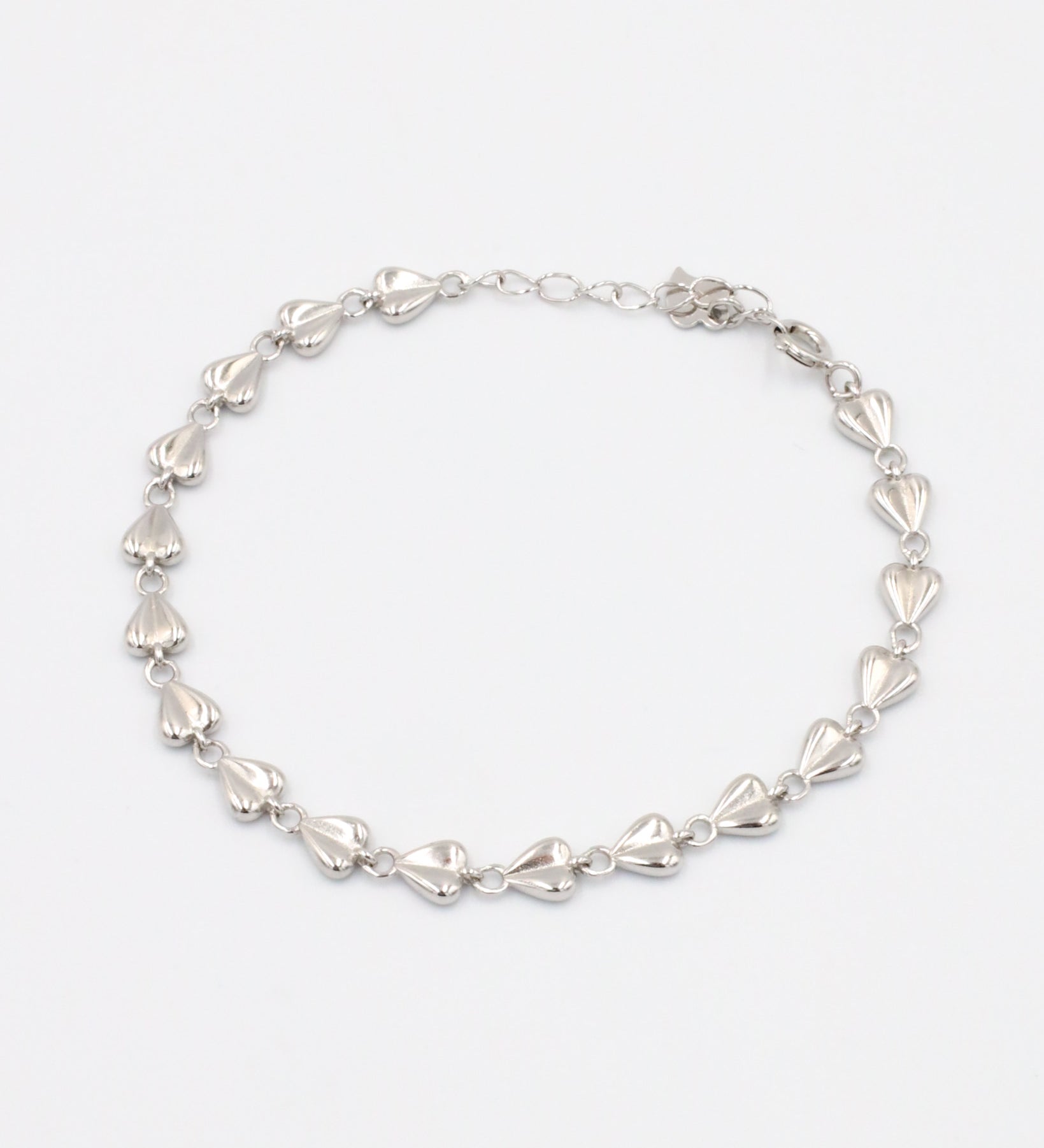 A silver bracelet with a heart-shaped pattern on a white background