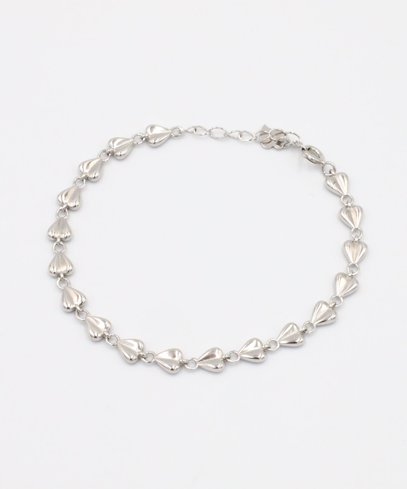 A silver bracelet with a heart-shaped pattern on a white background