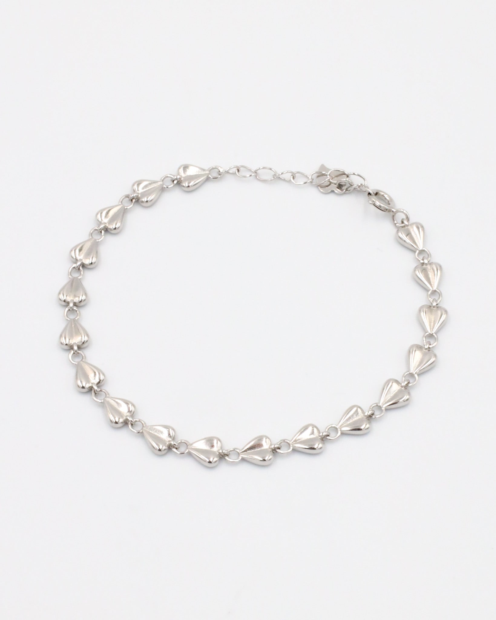A silver bracelet with a heart-shaped pattern on a white background