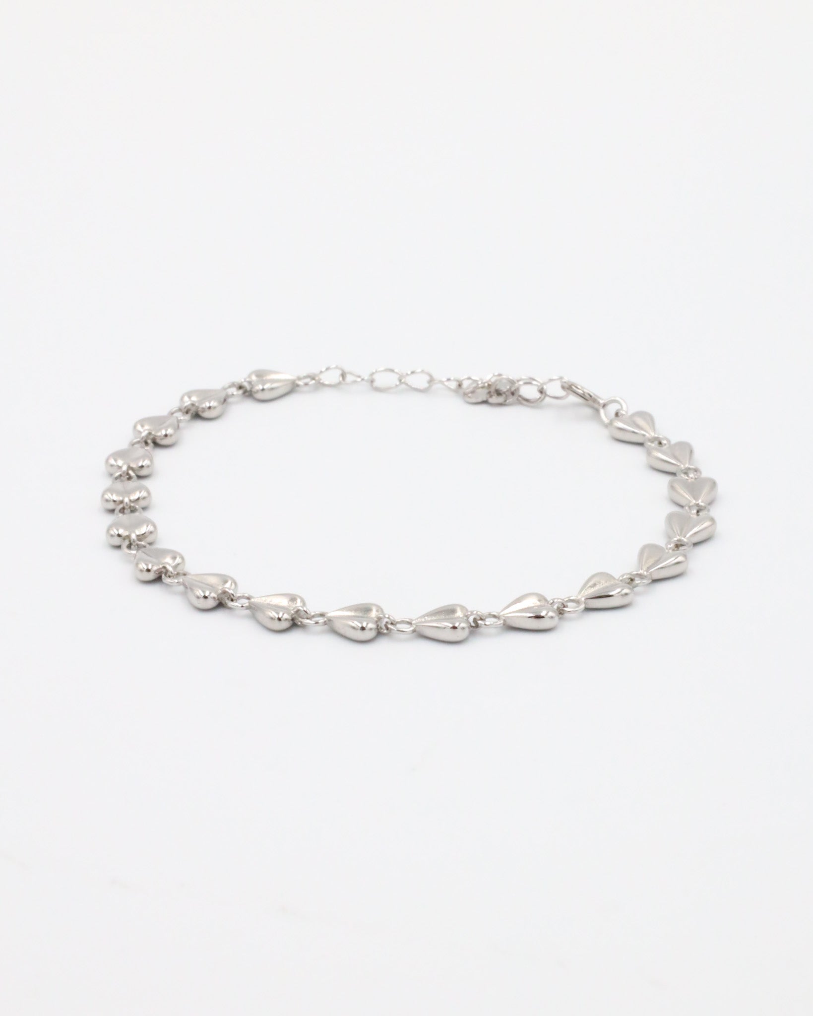 A silver bracelet with a heart-shaped pattern on a white background