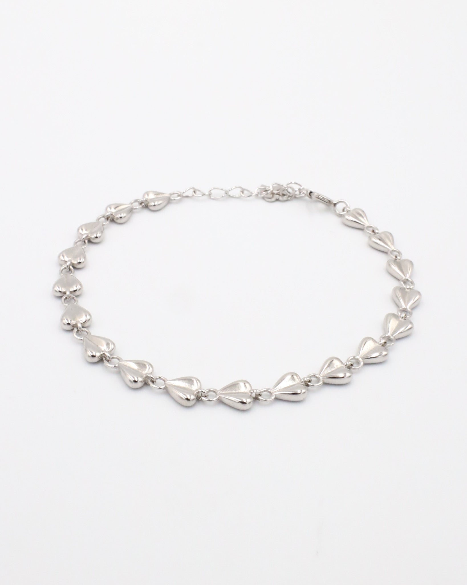 A silver bracelet with a heart-shaped pattern on a white background