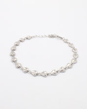 A silver bracelet with a heart-shaped pattern on a white background