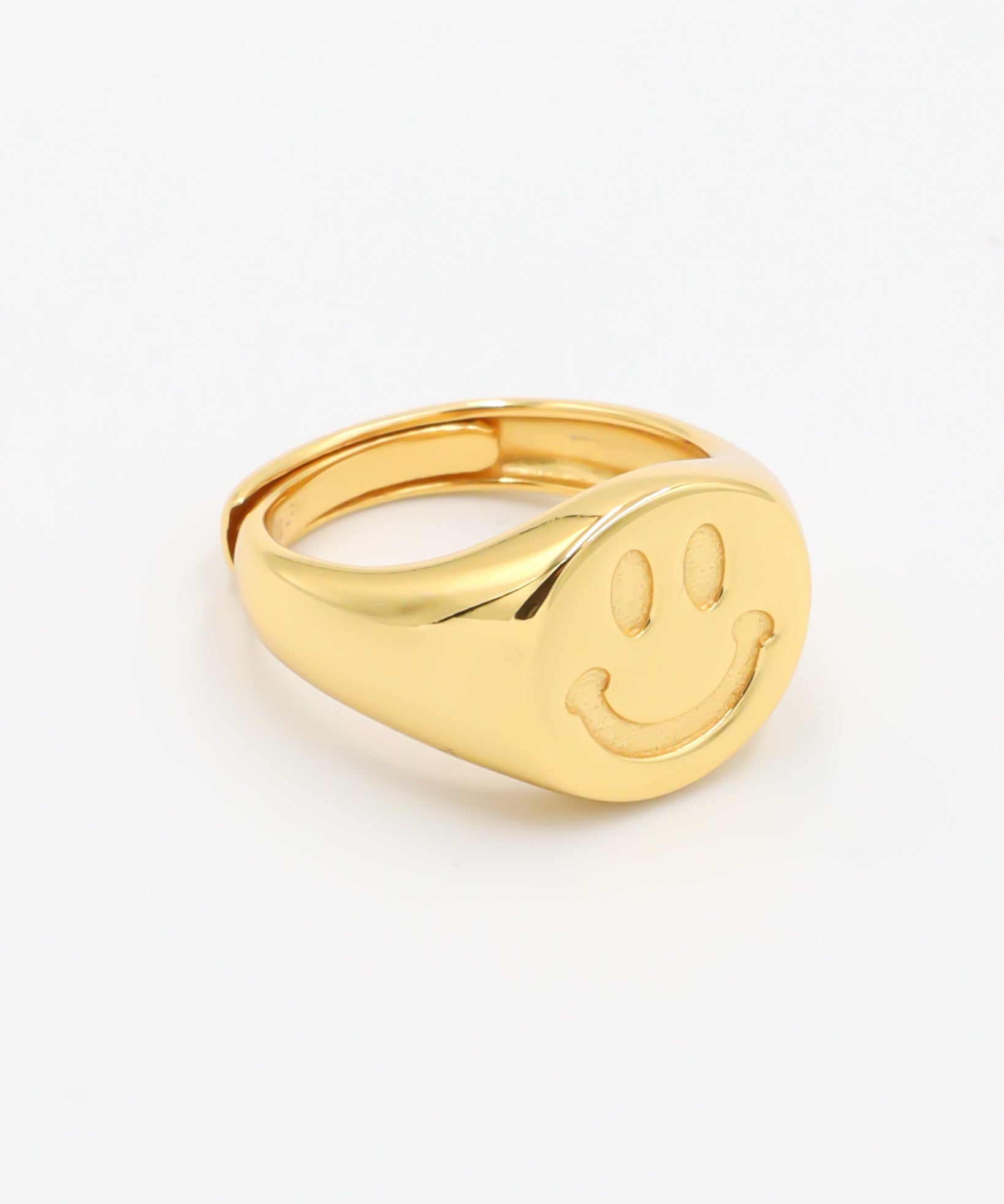 A gold-colored ring with a smiley face design on the top surface.