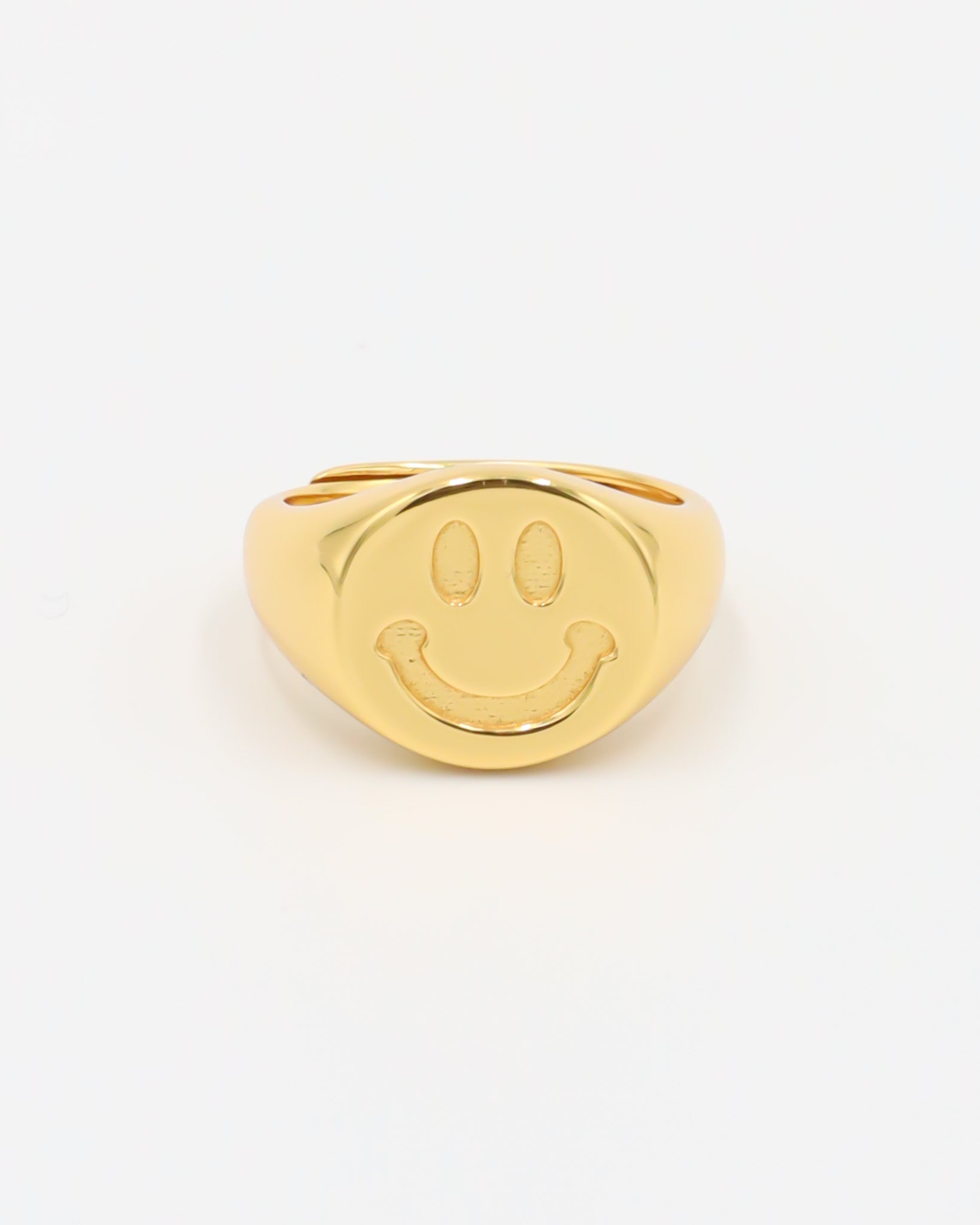 A gold-colored ring with a smiley face design on the top surface.