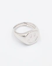 A silver ring with a solid pattern and a rounded band, displayed against a white background.