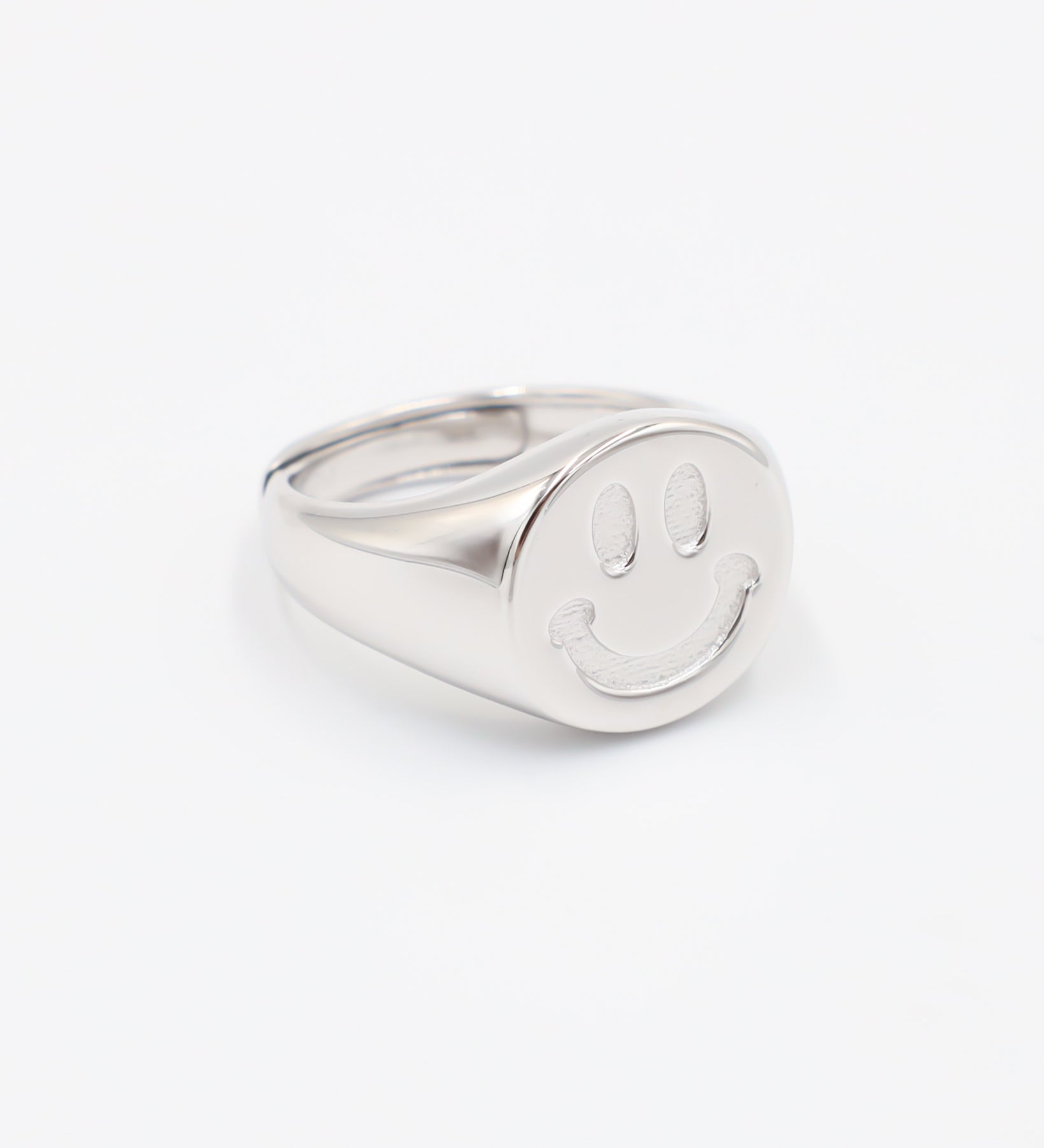 A silver ring with a solid pattern and a rounded band, displayed against a white background.