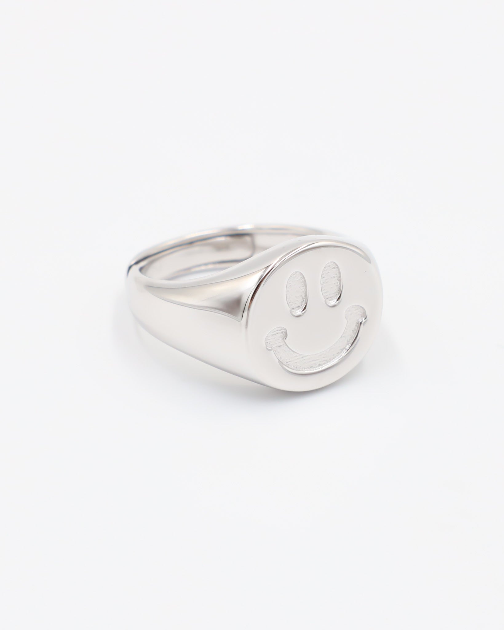 A silver ring with a solid pattern and a rounded band, displayed against a white background.