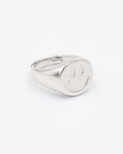 A silver ring with a solid pattern and a rounded band, displayed against a white background.