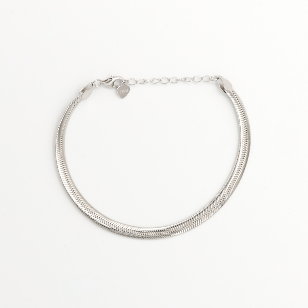 A silver bracelet with two chain layers and heart-shaped charms on it, displayed against a white background.