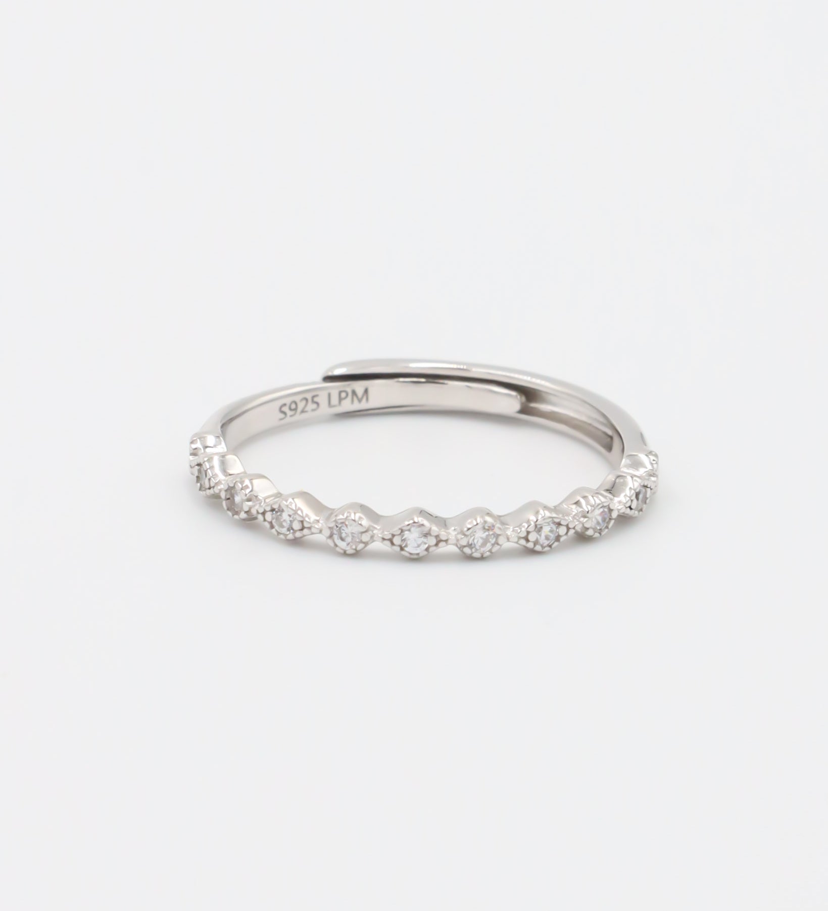 A silver ring with multiple gemstones set around its circumference, displayed against a white background.