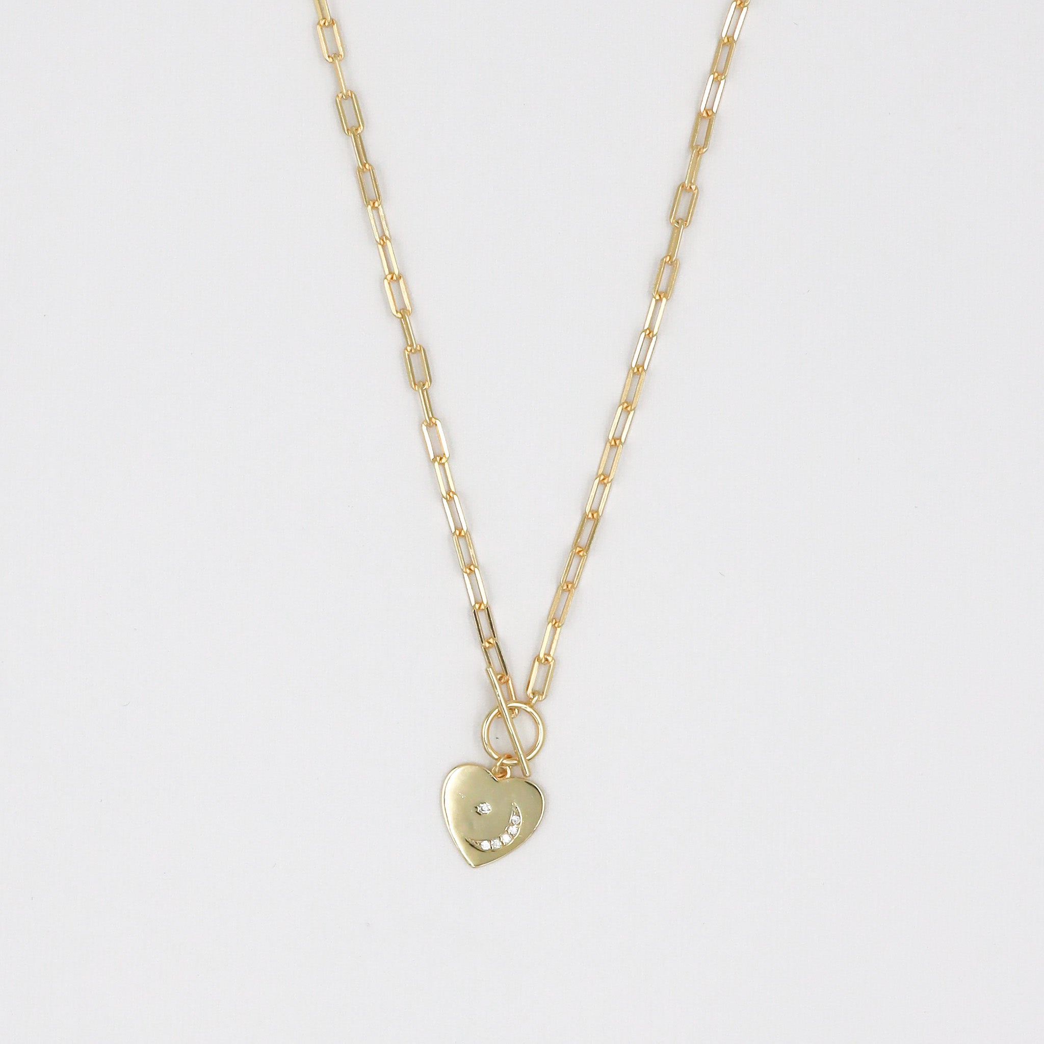 A gold-colored necklace with a heart-shaped pendant on a chain.