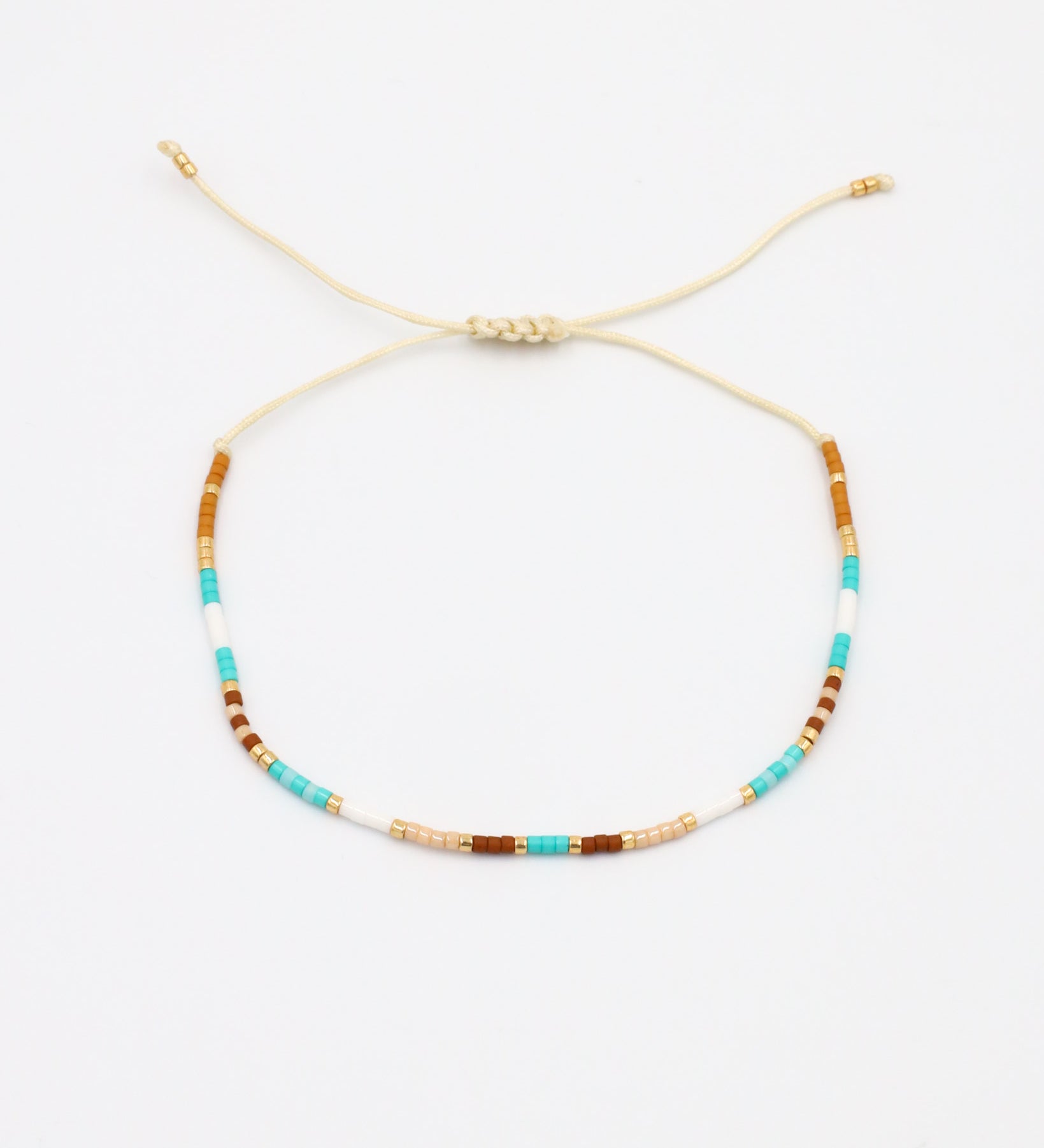 A beaded bracelet with a mix of gold and turquoise colors, featuring rhinestones and an adjustable cord.