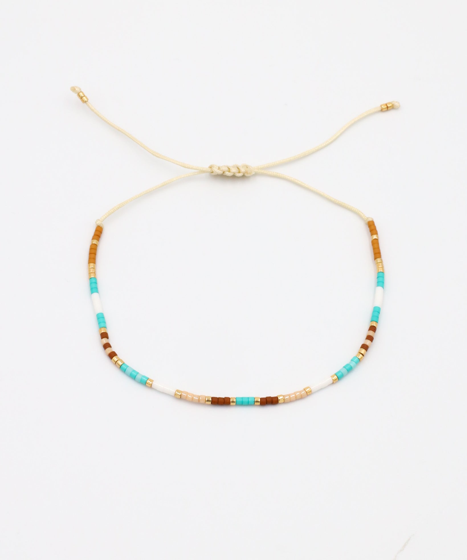 A beaded bracelet with a mix of gold and turquoise colors, featuring rhinestones and an adjustable cord.