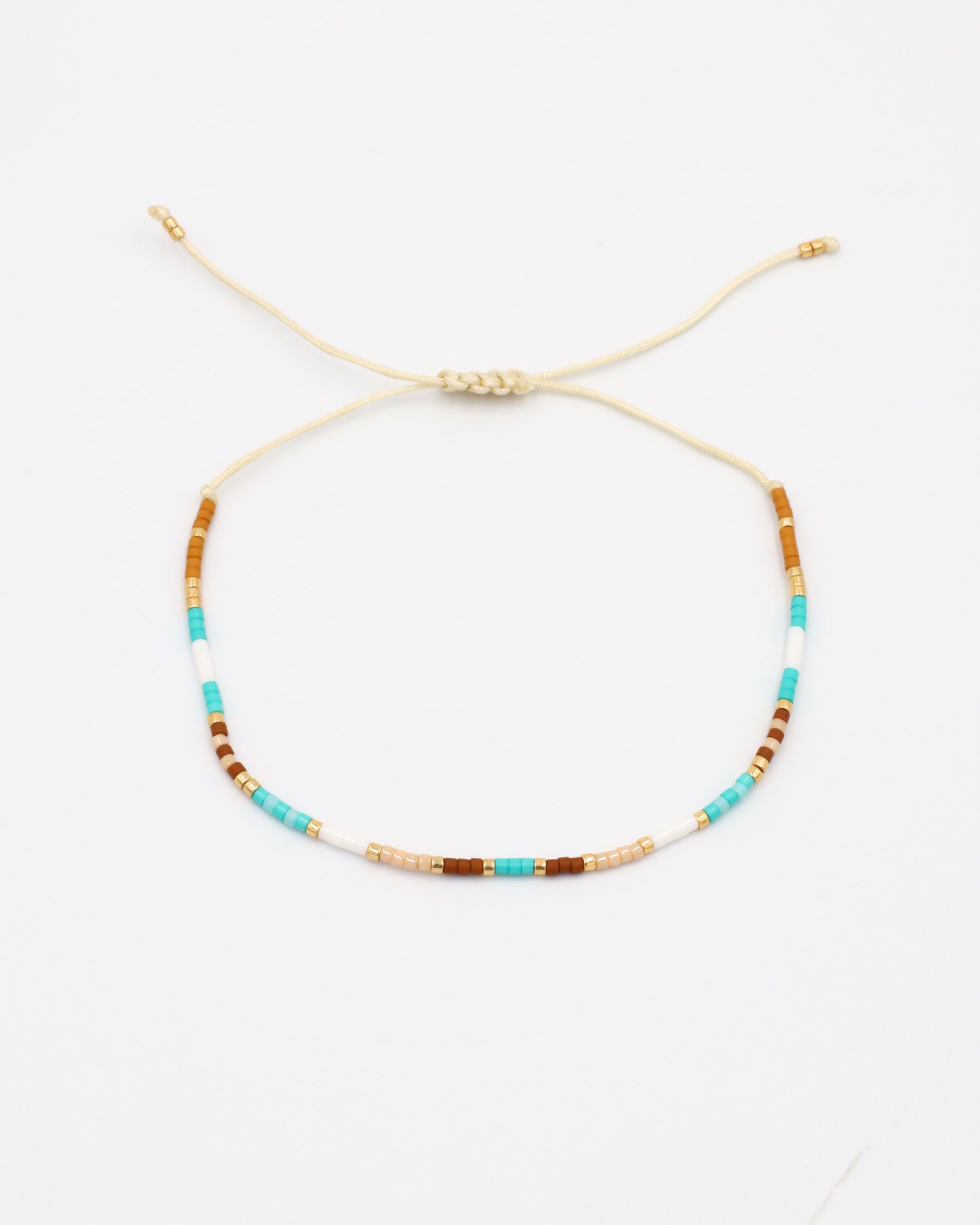 A beaded bracelet with a mix of gold and turquoise colors, featuring rhinestones and an adjustable cord.