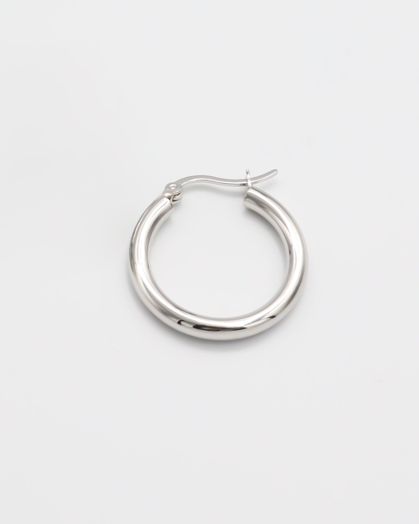 A pair of silver hoop earrings with a latch back closure on a white background