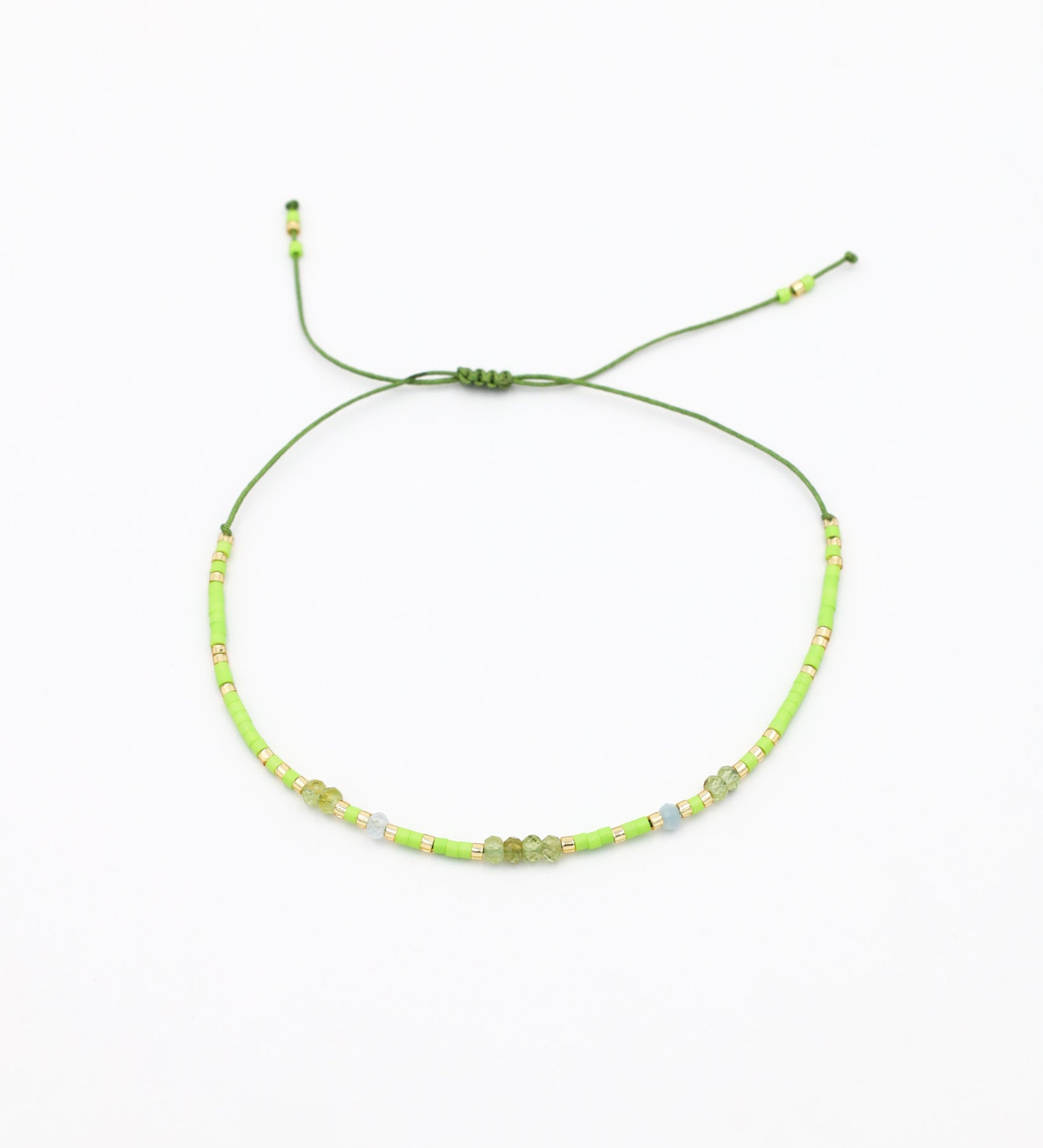An adjustable beaded necklace with green and gold-colored beads and rhinestones on a white background.