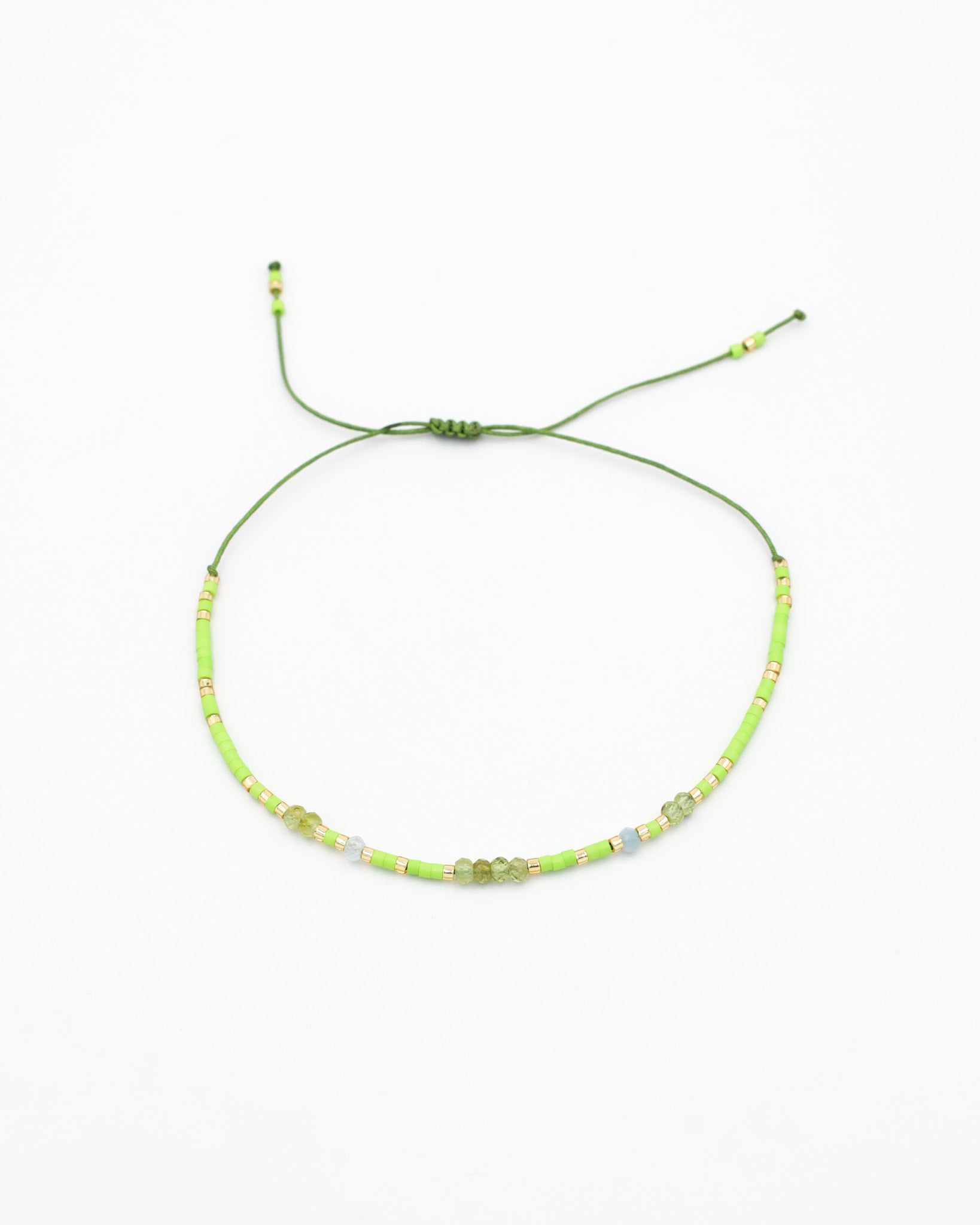 An adjustable beaded necklace with green and gold-colored beads and rhinestones on a white background.
