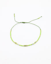 An adjustable beaded necklace with green and gold-colored beads and rhinestones on a white background.