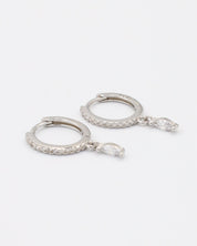 A silver-colored hoop earring with a small dangling gemstone attached, displayed against a white background.