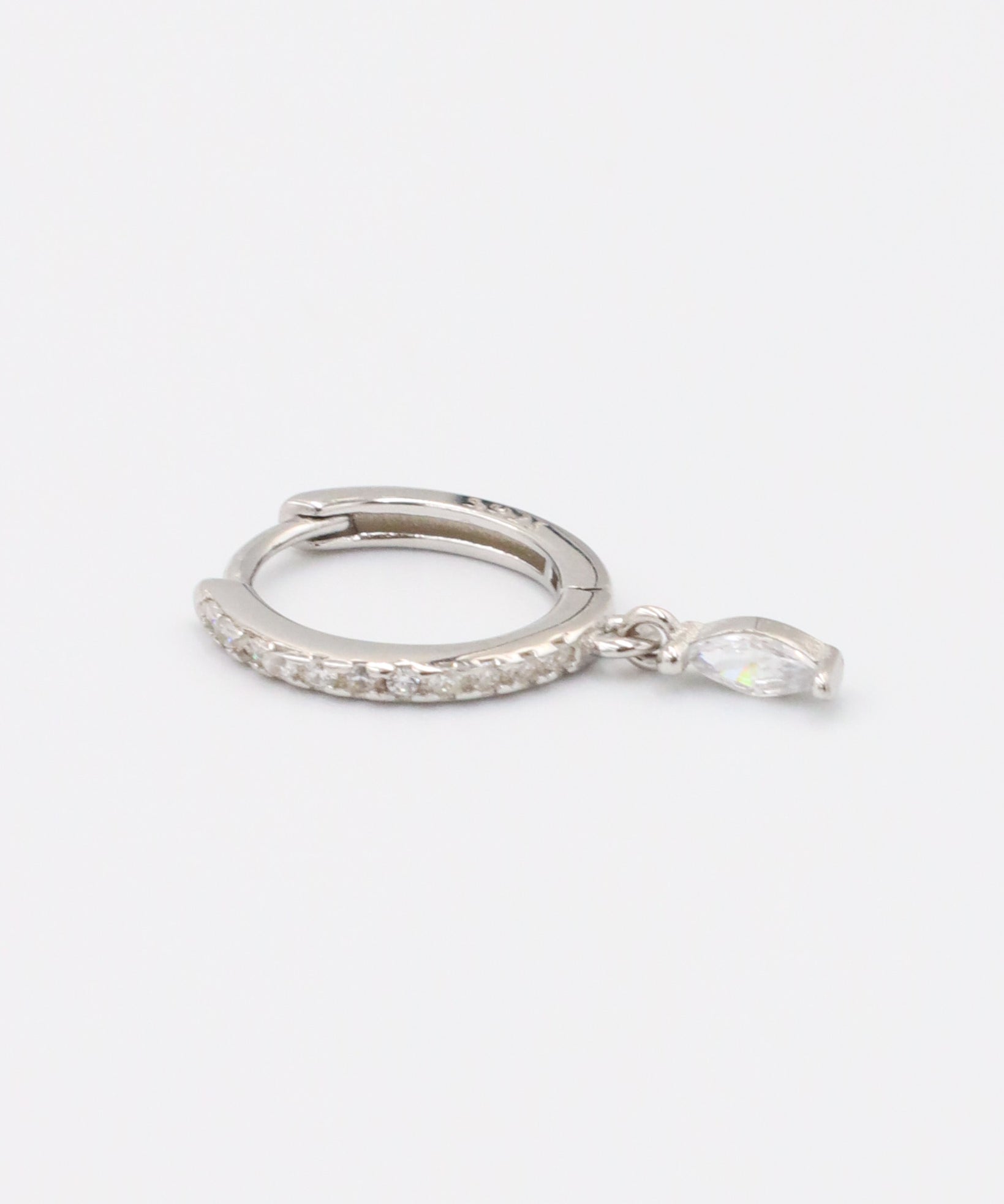 A silver-colored hoop earring with a small dangling gemstone attached, displayed against a white background.
