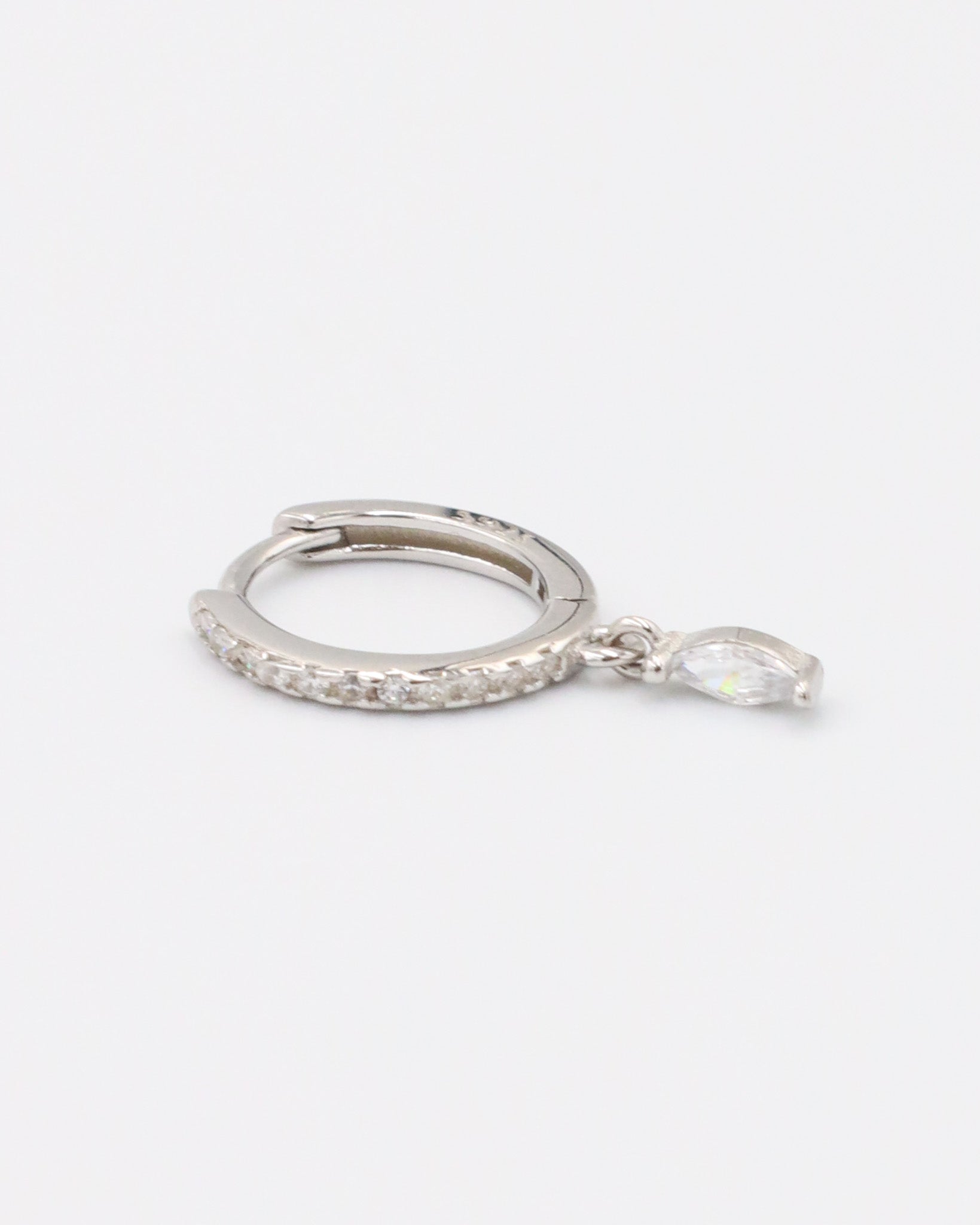 A silver-colored hoop earring with a small dangling gemstone attached, displayed against a white background.