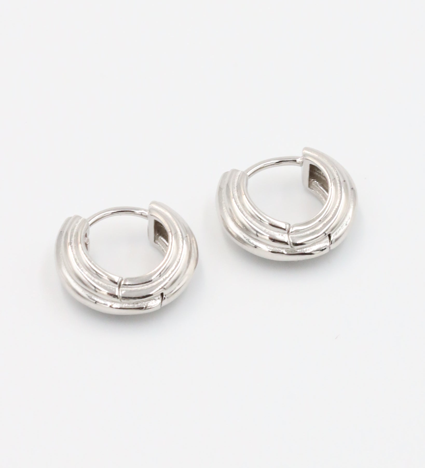 A pair of silver hoop earrings with a hinged clasp closure.