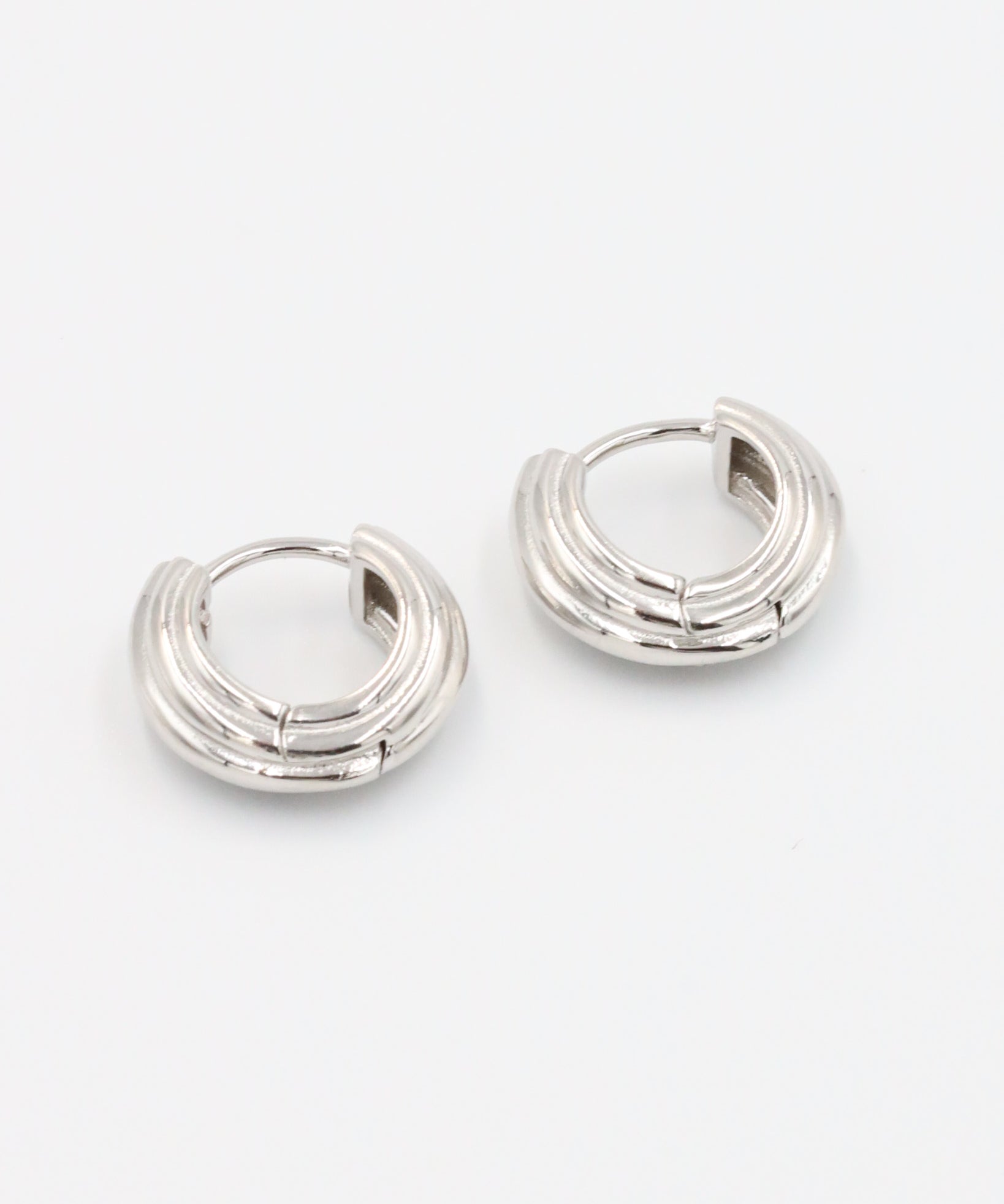 A pair of silver hoop earrings with a hinged clasp closure.