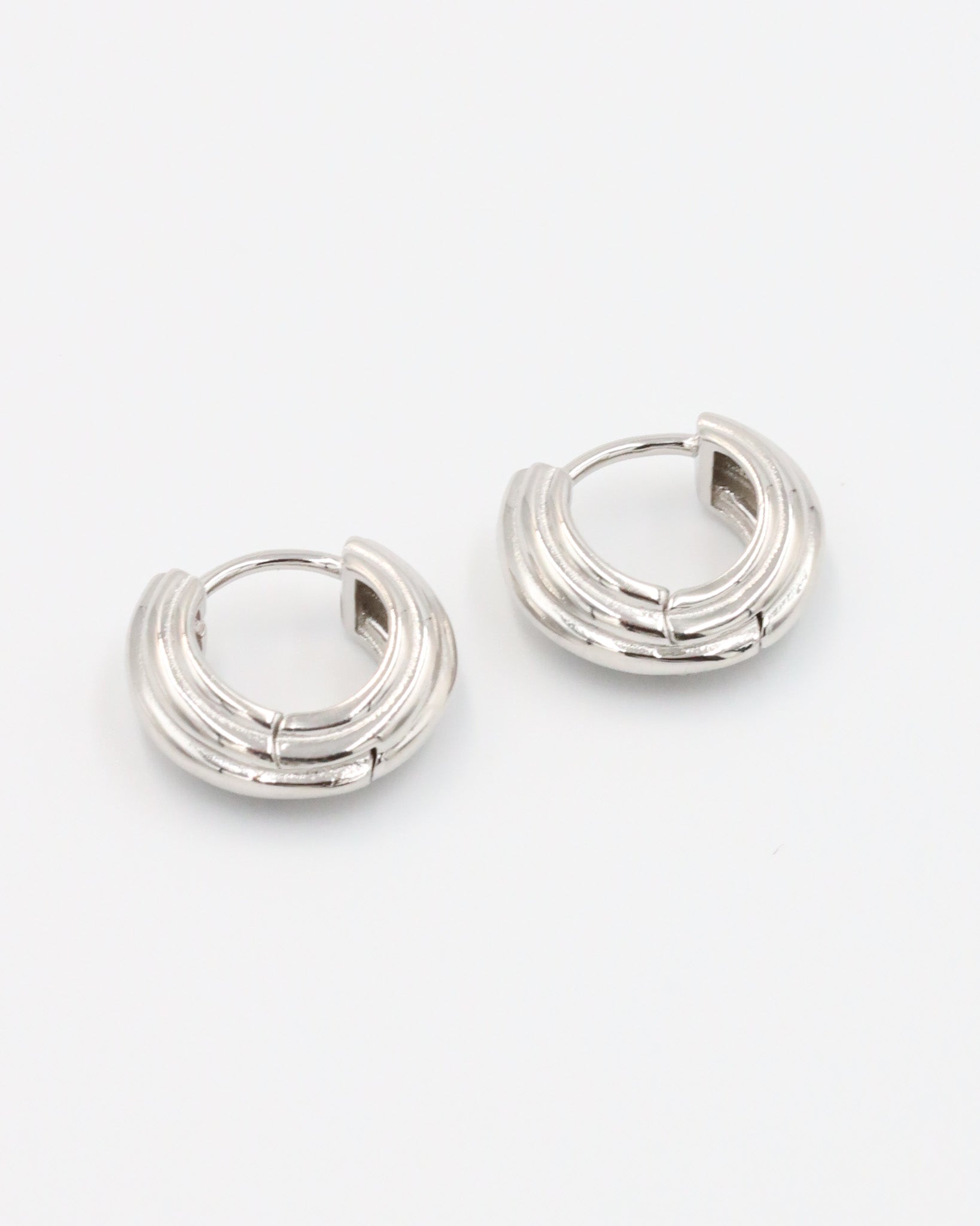 A pair of silver hoop earrings with a hinged clasp closure.