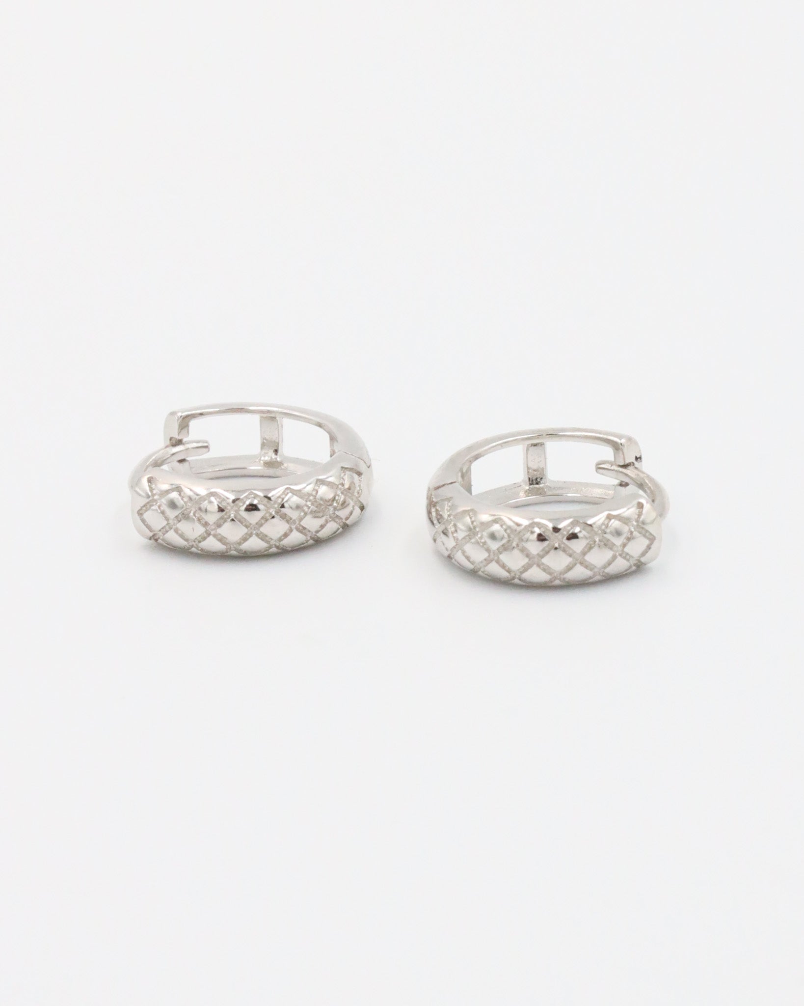 A single silver hoop earring with a geometric pattern and a hinged clasp.