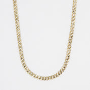 A gold-colored necklace with a curb chain link on a white background.