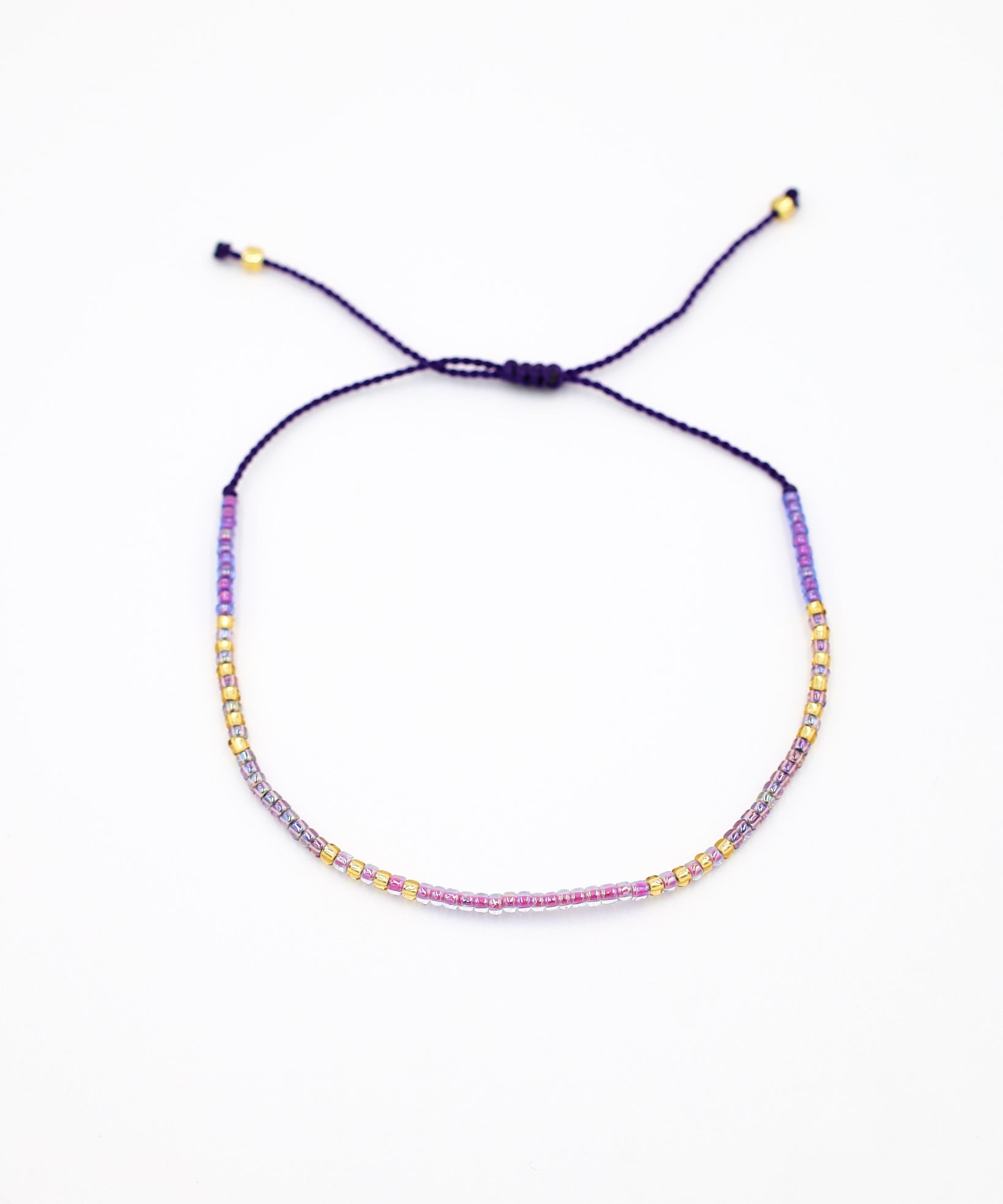 An adjustable gold-colored bracelet with a series of round beads and rhinestones strung on a dark strand.