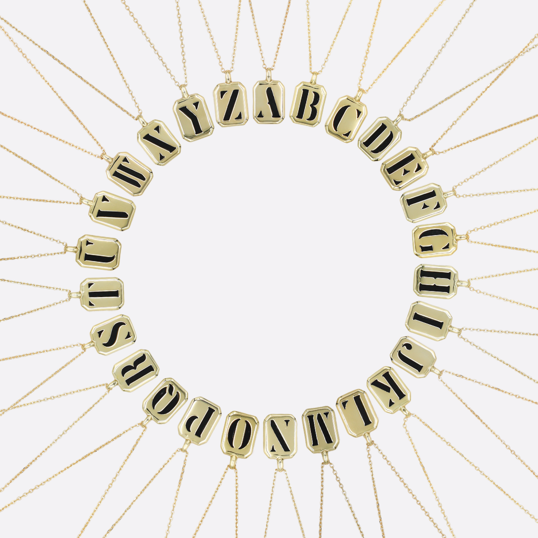 A collection of gold-colored letter necklaces displayed in a circular arrangement with the letters of the alphabet.