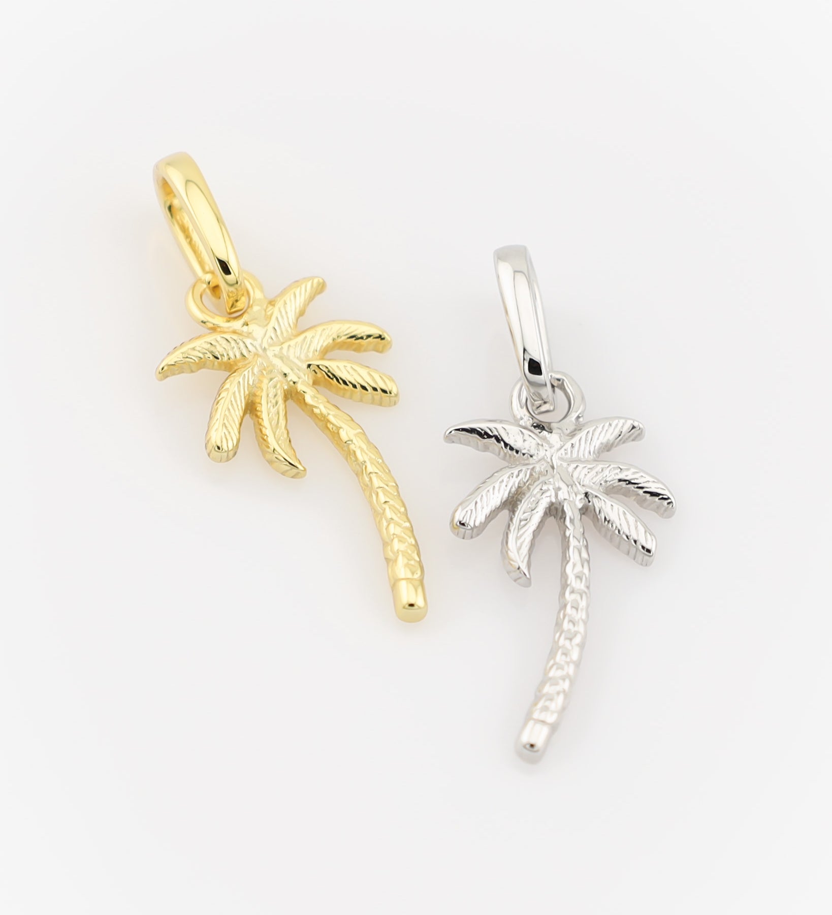 Gold and silver palm tree pendants on a white background