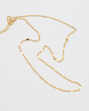 Loretta Necklace in gold-plated 925 sterling silver, laid out to show its dainty chain design.