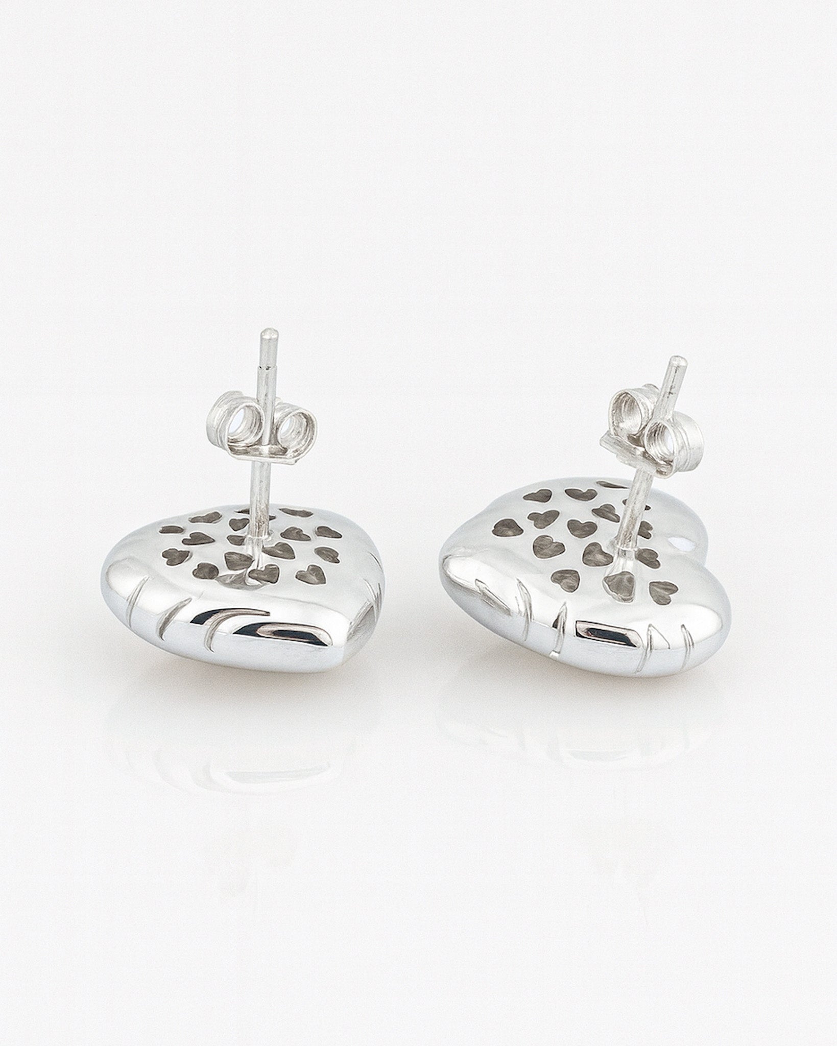 Pair of silver heart-shaped earrings with cut-out heart designs on a white background