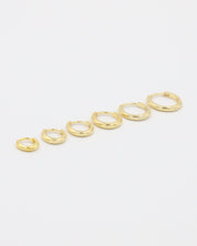A series of circular gold colored hoops of varying sizes arranged in a line on a white background.