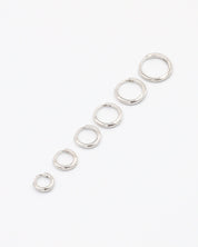 A series of circular silver hoops of varying sizes arranged in a line on a white background.