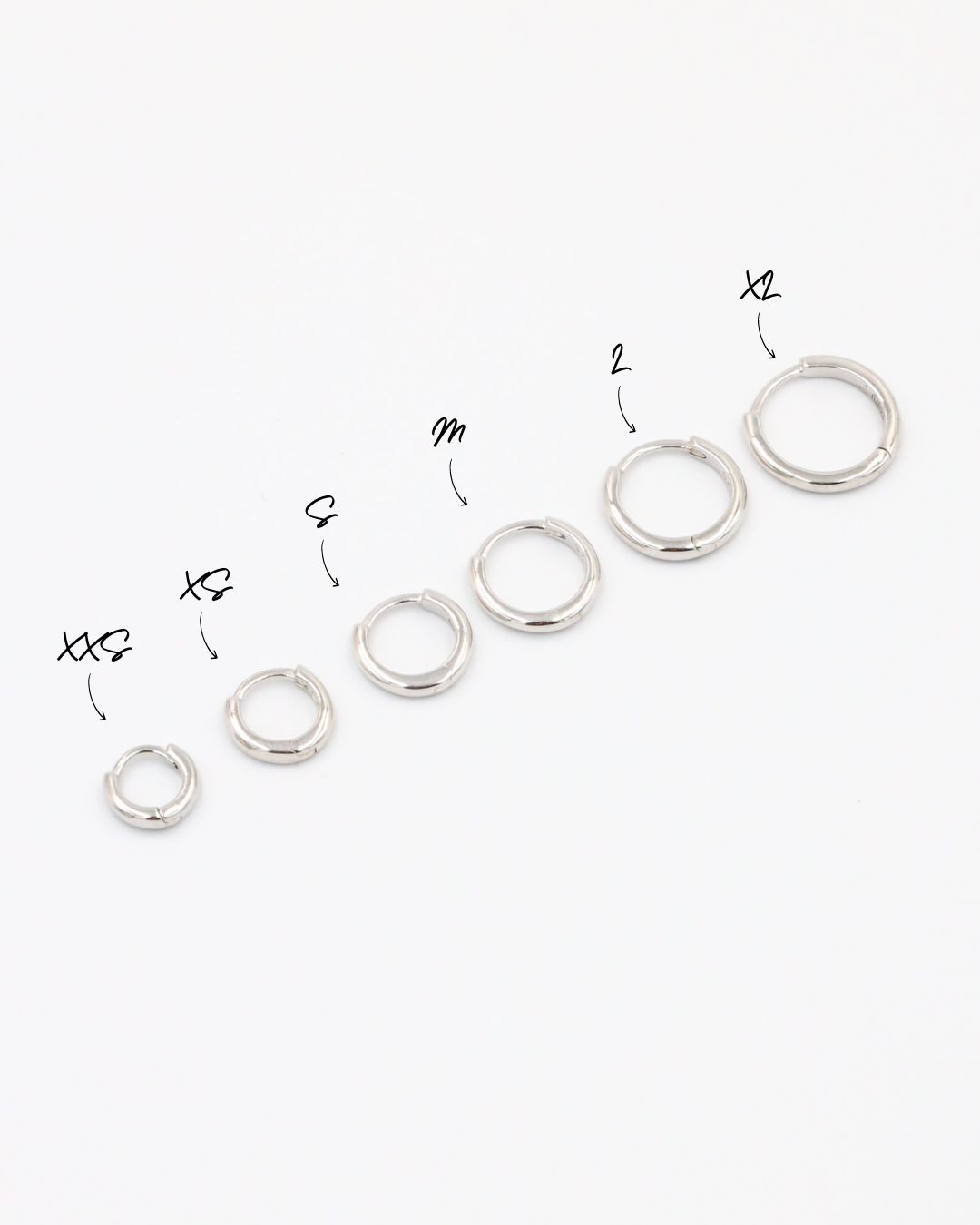 A series of circular silver colored hoops of varying sizes arranged in a line on a white background.