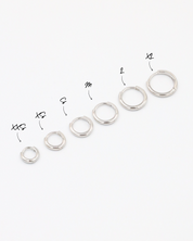 A series of circular silver colored hoops of varying sizes arranged in a line on a white background.