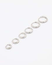 A series of circular silver colored hoops of varying sizes arranged in a line on a white background.