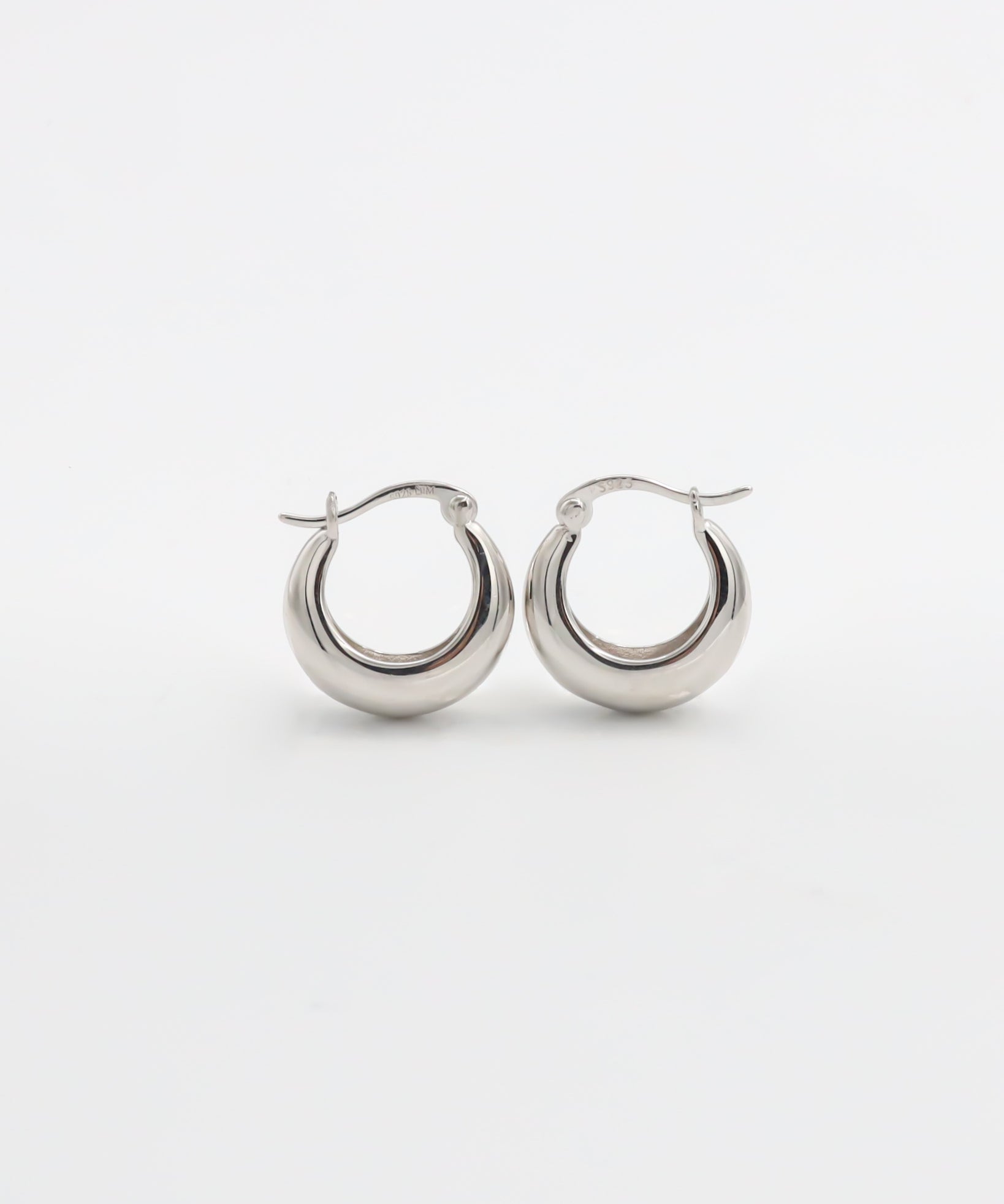 A pair of silver hoop earrings with a latch back closure on a white background