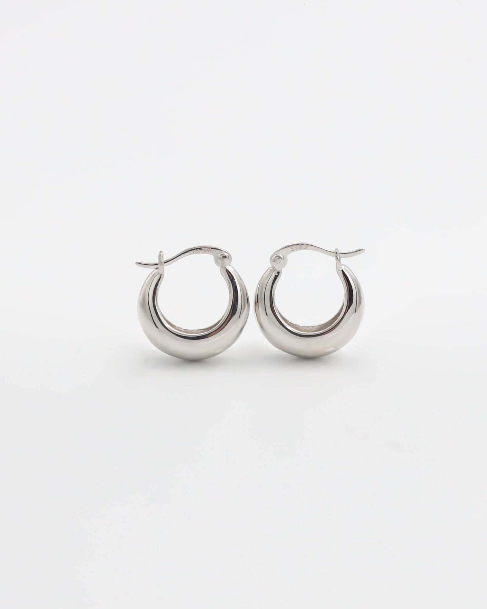 A pair of silver hoop earrings with a latch back closure on a white background