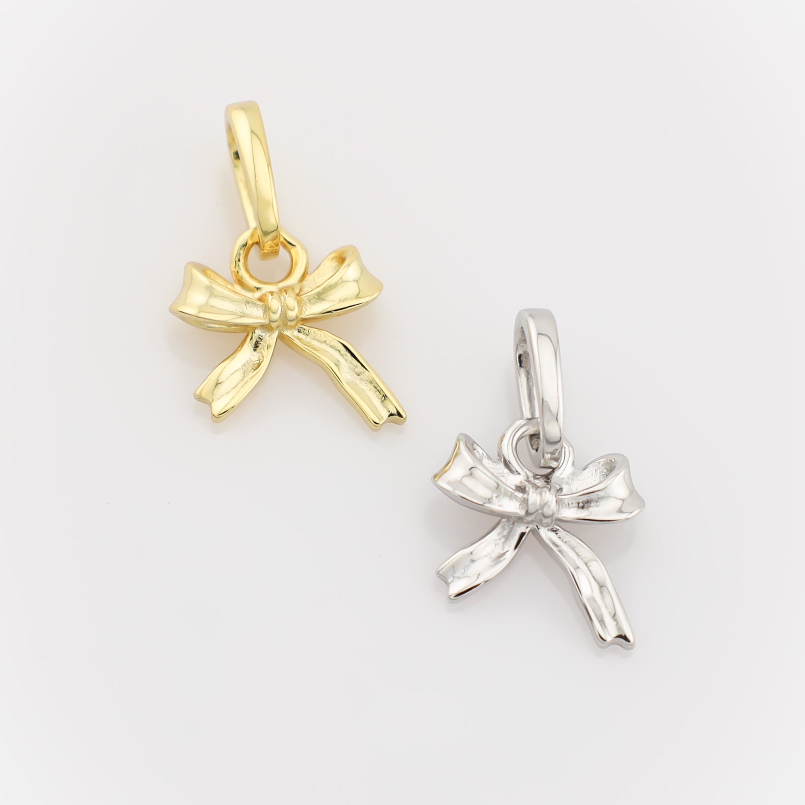 Gold and silver bow-shaped pendants on a light gray background