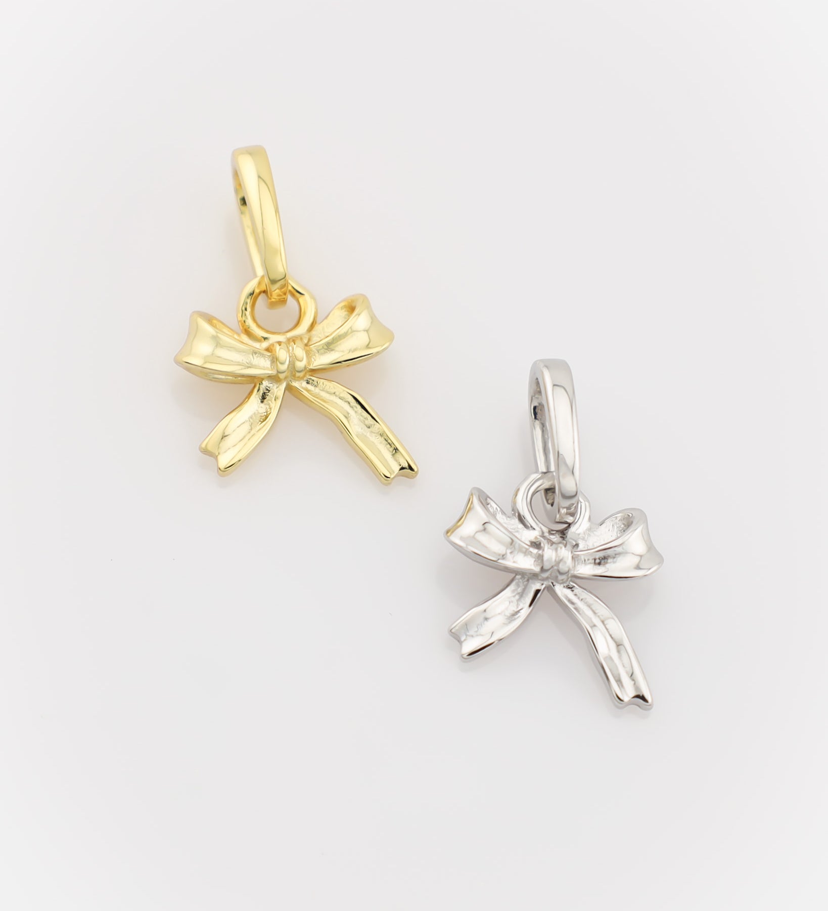 Gold and silver bow-shaped pendants on a light gray background
