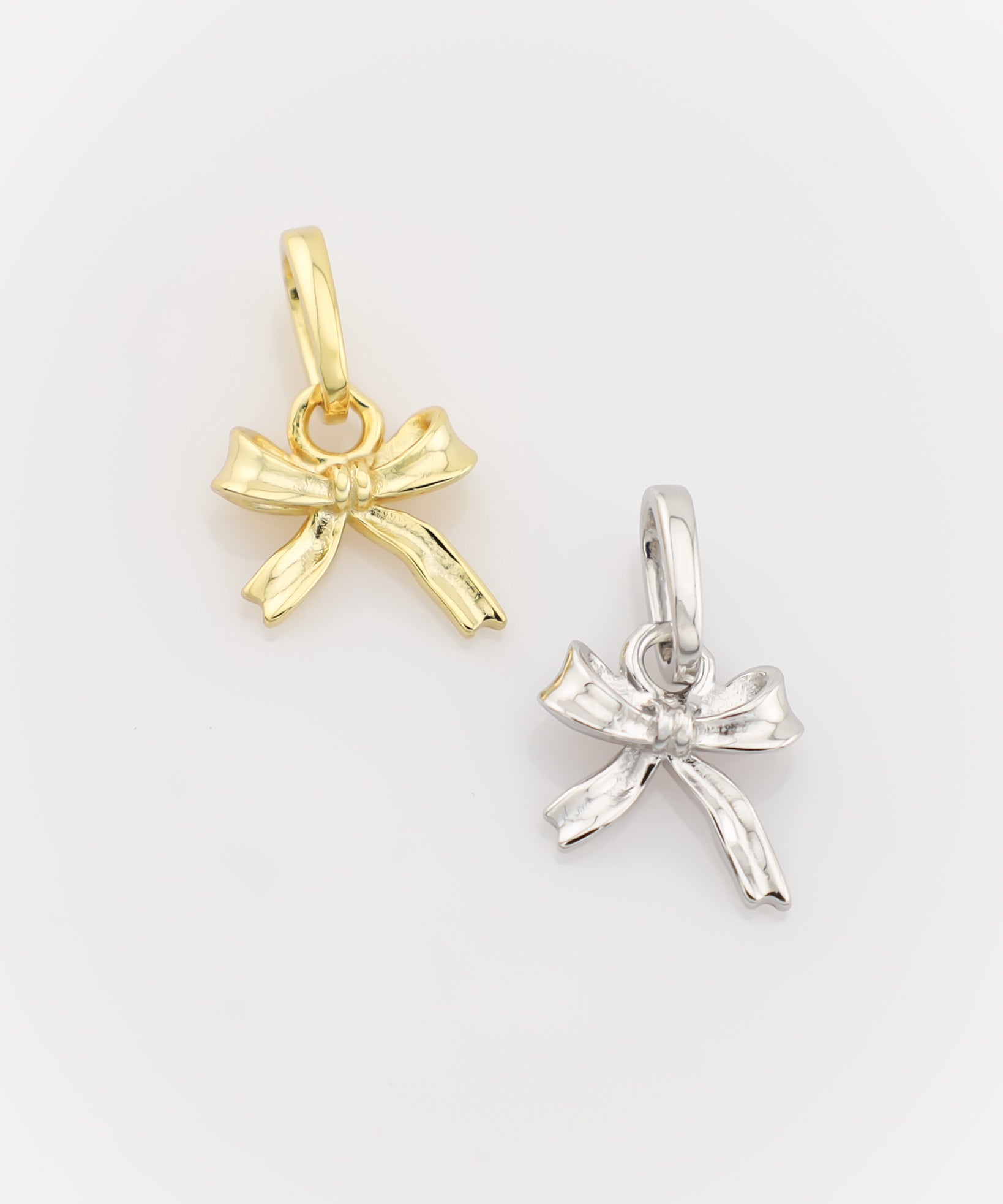 Gold and silver bow-shaped pendants on a light gray background