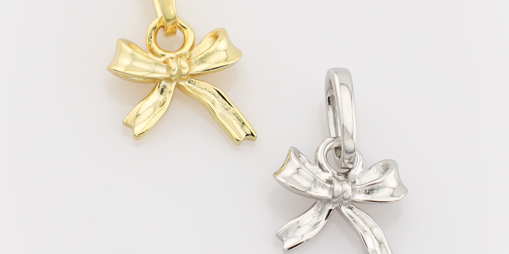 Gold and silver bow-shaped pendants on a light gray background