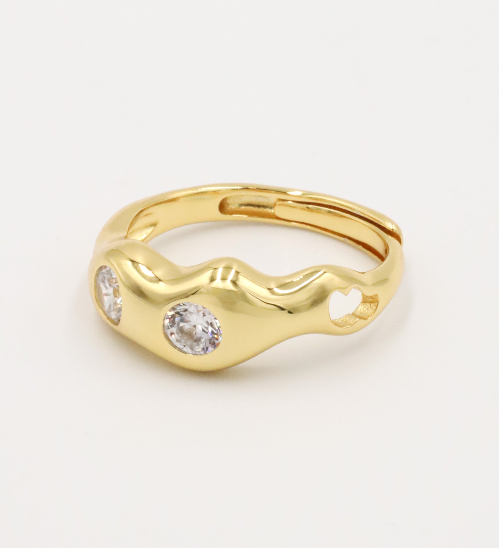A gold-colored ring with two clear stones set in a wave-like design.