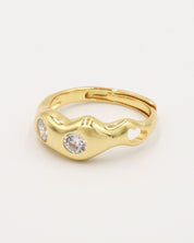A gold-colored ring with two clear stones set in a wave-like design.